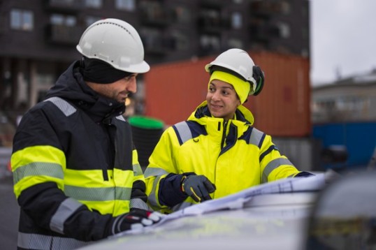 Färgfotografi: Två byggjobbare tittar på en ritning