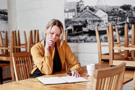 Bekymrad kvinna klurar på ekonomin i en tom restaurang efter stängning.