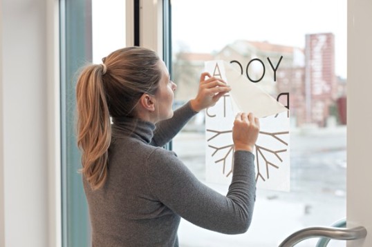 En tjej klistrar företagets logotyp på dörren till sin yogastudio.